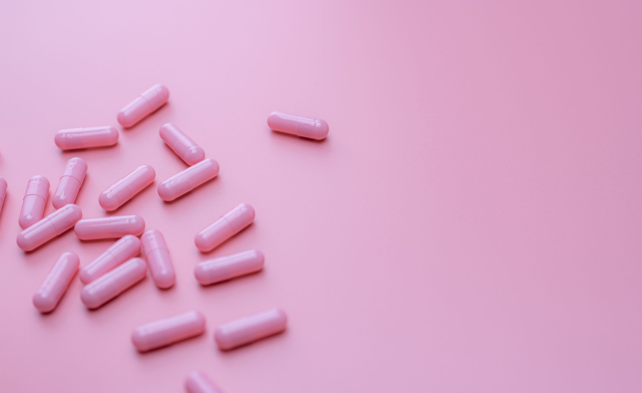 Pink Capsules Pill Spread on Pink Background. Vitamin and Supple